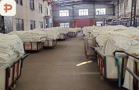 Greige plush fabric stacked in trolleys before dyeing